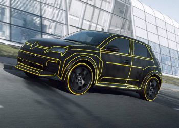 Camouflaged Renault 5 driving on road next to factory