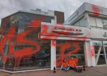 Climate activists sitting outside of vandalised luxury car dealership in Wellington