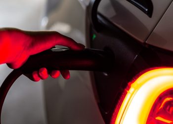 Person's hand on Tesla EV charging plug