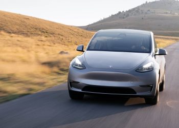 Tesla Model Y driving past field