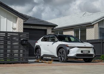 Toyota bZ4X Pure, in white and black, in front of a new house