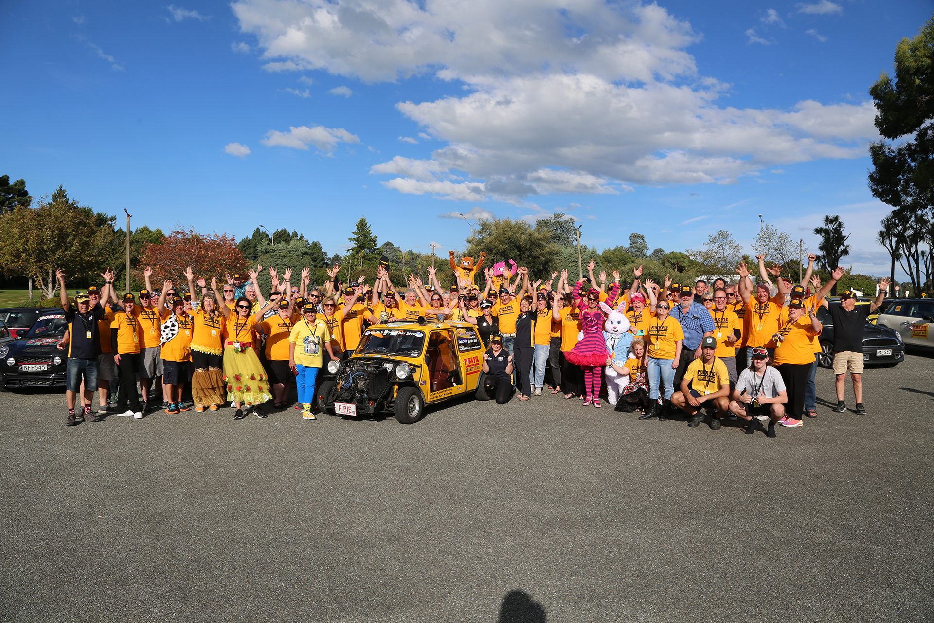 Pork Pie Charity Run lots of people around a yellow mini that is missing its bonnet