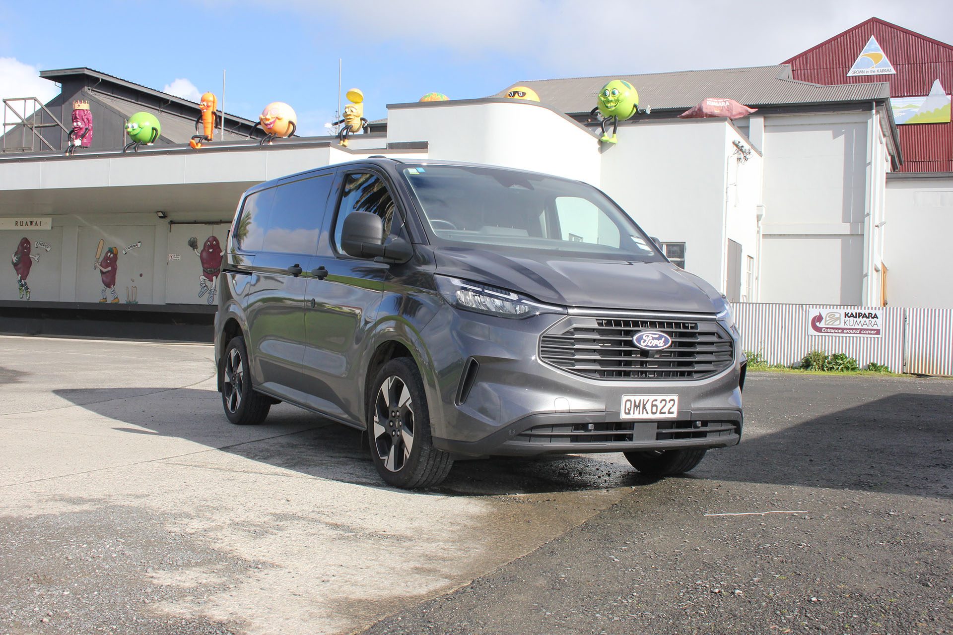Grey Ford Transit Custom in front of white warehouse
