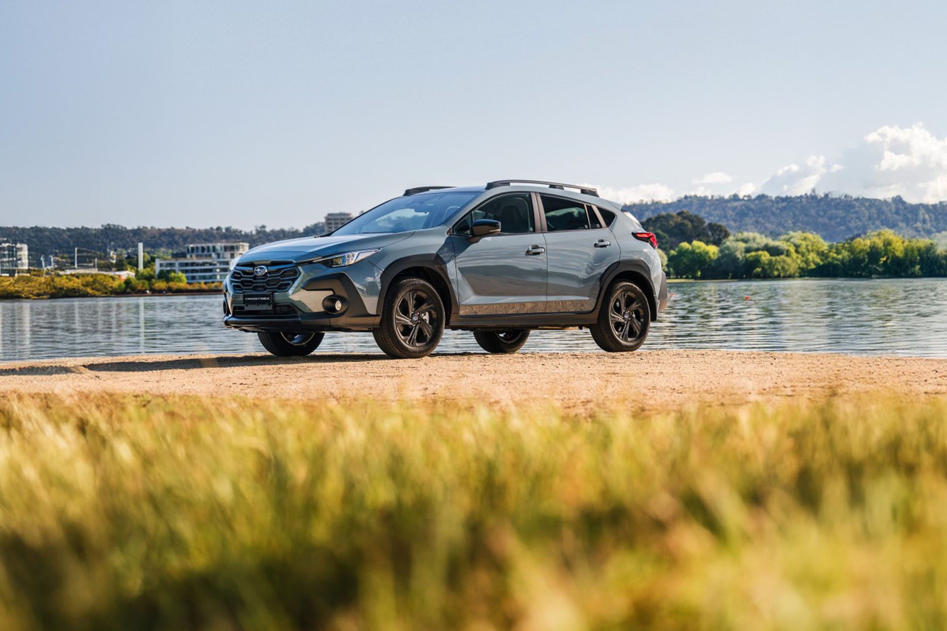 Subaru Crosstrek in front of a lake with grass in the foreground