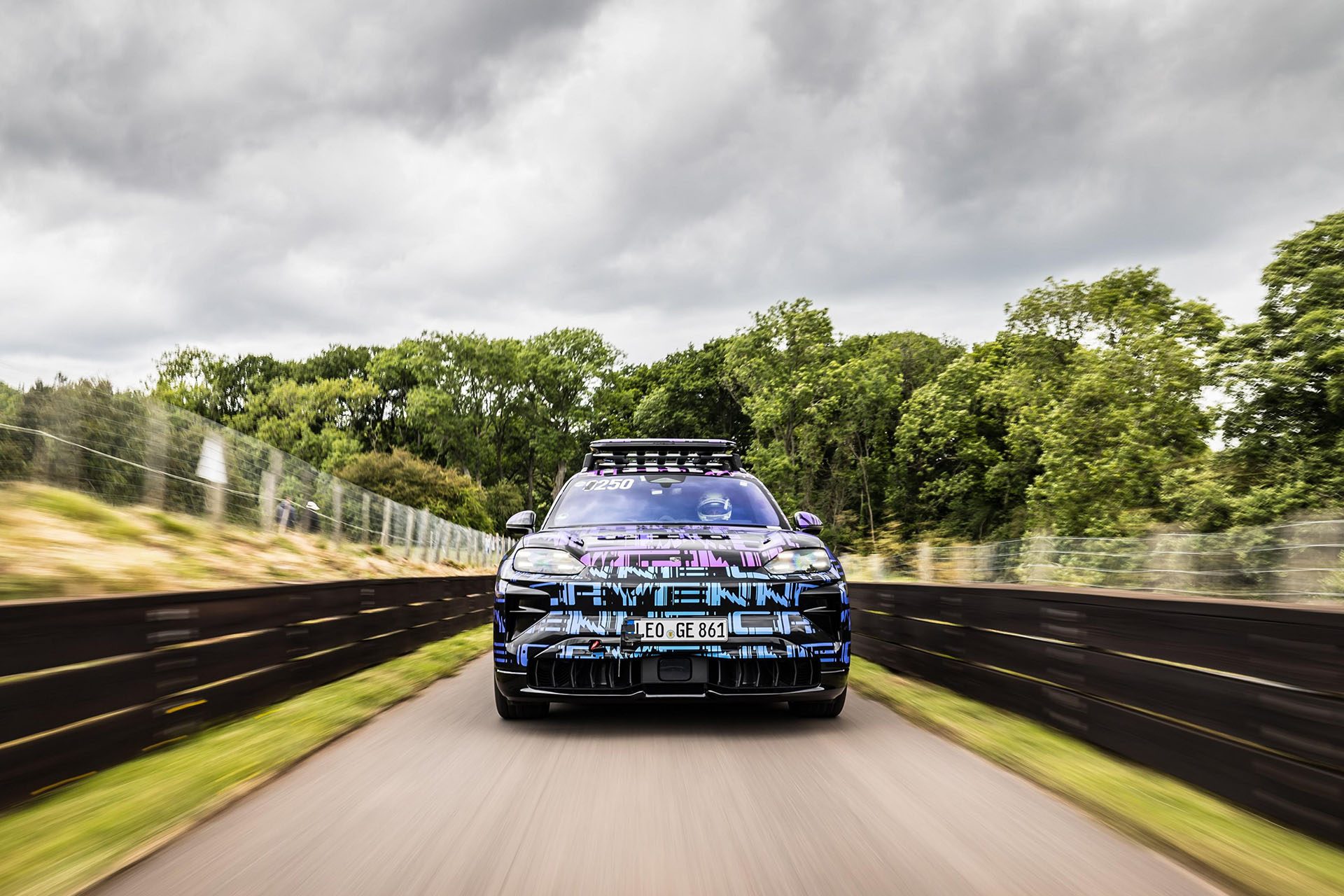 Porsche Cayenne EV on the start line with armco each side and trees behind