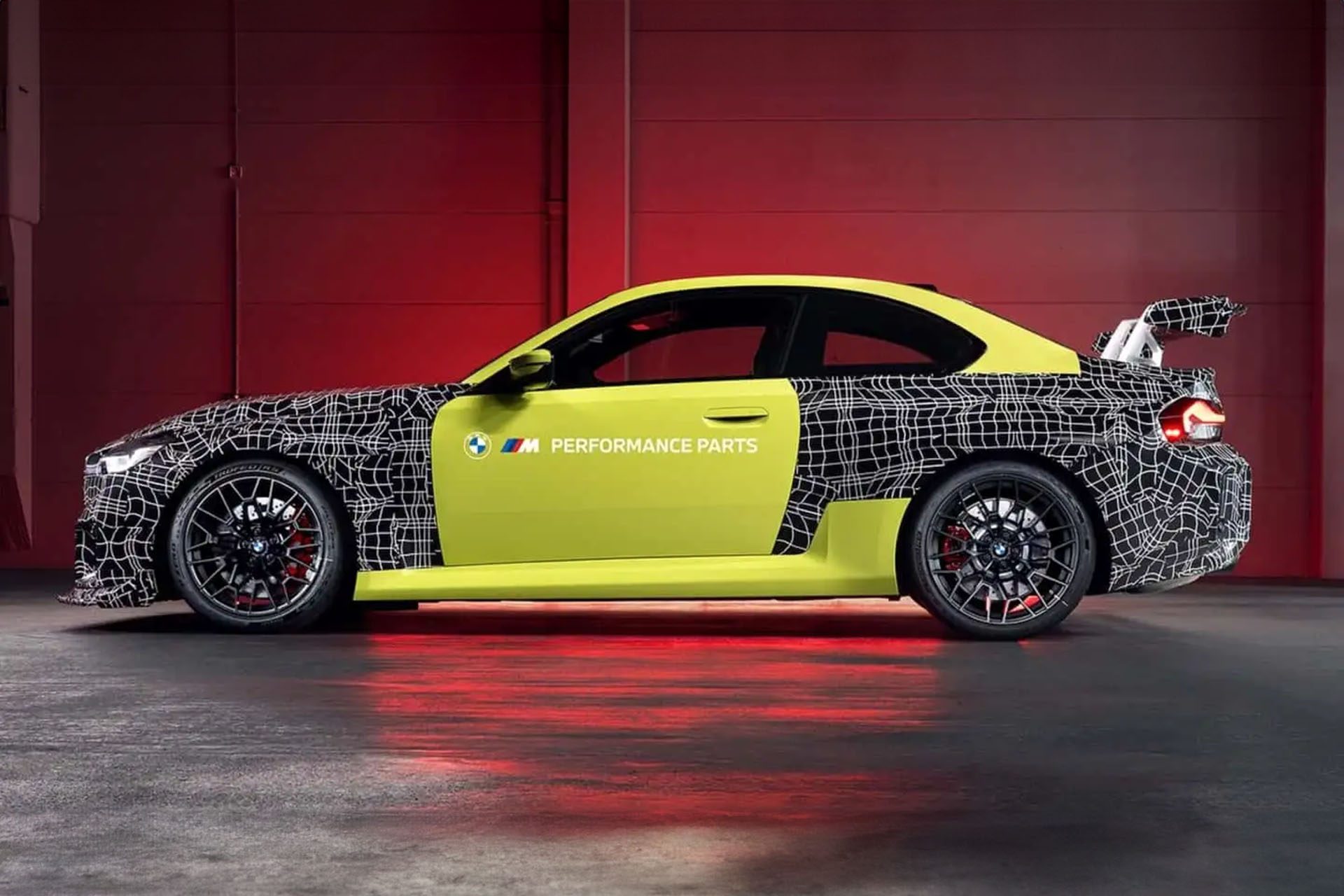 BMW M2 with aero kit in front of a red wall